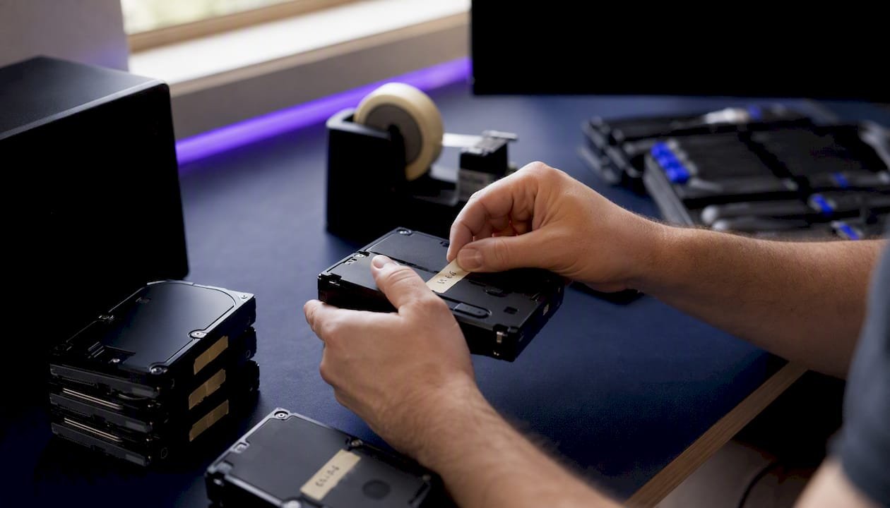 Hands labelling NAS hard drives before removal
