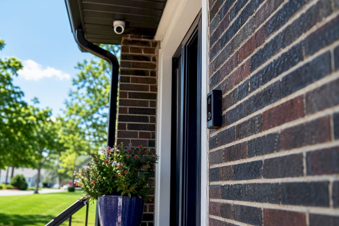 Video doorbell and under-eaves security camera covering a front porch